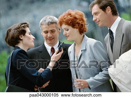 Group of four business people outside, one holding cell phone View Large Photo Image Stock Photography - Group of four business people outside, one holding cell phone. Fotosearch