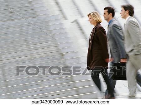 Three business people walking side by side, side view, blurred View Large Photo Image Stock Photo - Three business people walking side by side, side view, blurred. Fotosearch