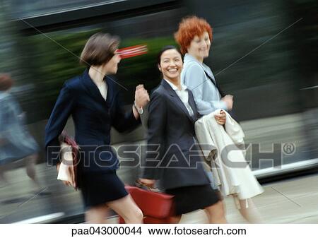 Three businesswomen walking in street, smiling, blurred View Large Photo Image Picture - Three businesswomen walking in street, smiling, blurred. Fotosearch
