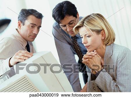 Two businessmen and a businesswoman looking at computer screen View Large Photo Image Stock Photo - Two businessmen and a businesswoman looking at computer screen. Fotosearch