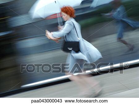 Woman in street walking under umbrella, blurred View Large Photo Image Stock Image - Woman in street walking under umbrella, blurred. Fotosearch