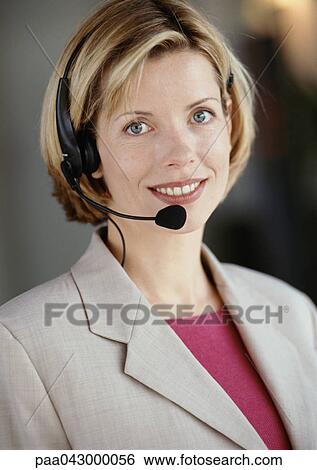 Stock Photograph - Woman wearing headset, smiling at camera, portrait. Fotosearch