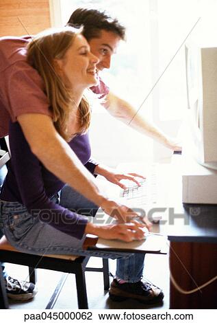 Couple looking at computer screen, man leaning over woman's shoulder, side view View Large Photo Image Stock Image - Couple looking at computer screen, man leaning over woman's shoulder, side view. Fotosearch