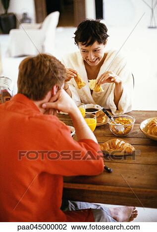 Couple sitting at table, having breakfast View Large Photo Image Stock Image - Couple sitting at table, having breakfast. Fotosearch