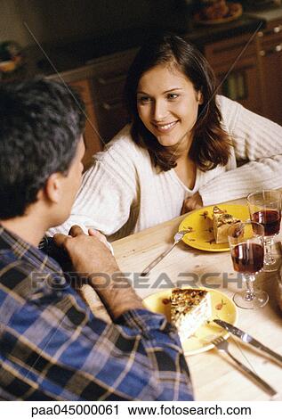 Stock Image - Man and woman at table, focus on woman in background. Fotosearch