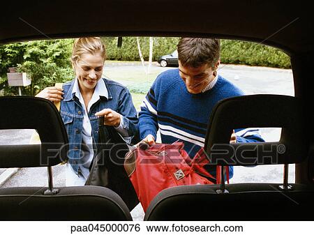 Man and woman putting bags in trunk of car, car headrests in foreground View Large Photo Image Stock Photograph - Man and woman putting bags in trunk of car, car headrests in foreground. Fotosearch