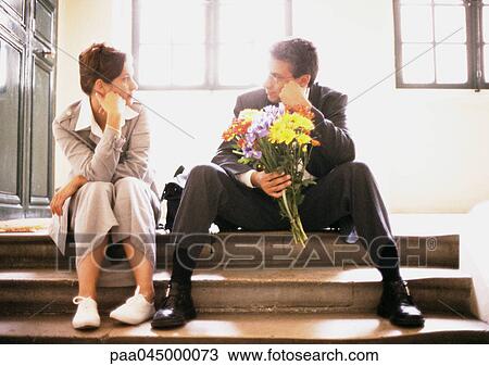Man and woman sitting on steps, looking at each other, man holding bouquet View Large Photo Image Stock Image - Man and woman sitting on steps, looking at each other, man holding bouquet. Fotosearch