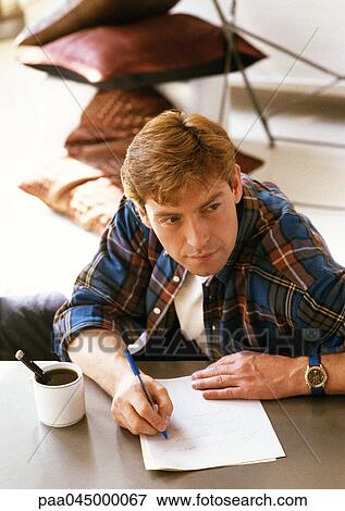 Man sitting at table, writing, high angle view View Large Photo Image Stock Photo - Man sitting at table, writing, high angle view. Fotosearch