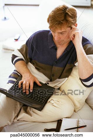 Stock Photograph - Man sitting, using laptop computer. Fotosearch