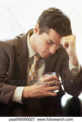 Man sitting with head against hand, holding glass, head and shoulders, close-up View Large Photo Image Stock Photo - Man sitting with head against hand, holding glass, head and shoulders, close-up. Fotosearch