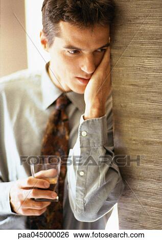 Man with hand against face leaning against wall and holding glass, close-up View Large Photo Image Stock Photograph - Man with hand against face leaning against wall and holding glass, close-up. Fotosearch