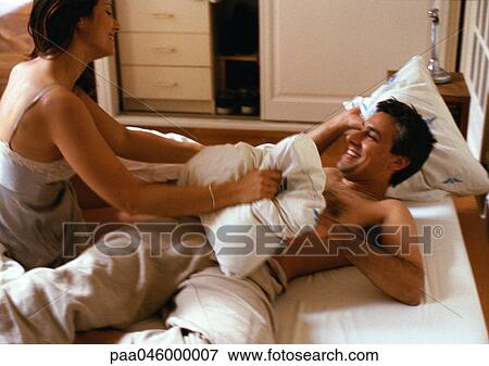 Stock Photo - Couple having pillow fight on bed. Fotosearch