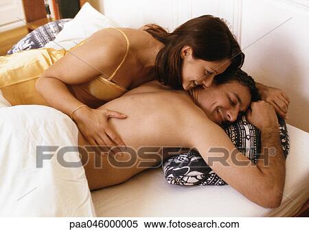 Couple lying in bed, woman with hand on man's side View Large Photo Image Stock Photography - Couple lying in bed, woman with hand on man's side. Fotosearch