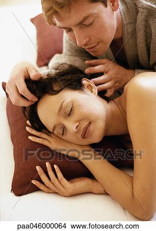 Couple lying on bed, man touching sleeping woman's hair View Large Photo Image Picture - Couple lying on bed, man touching sleeping woman's hair. Fotosearch