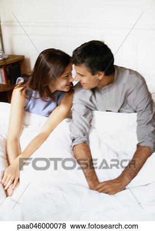 Couple sitting on bed, face to face View Large Photo Image Stock Photo - Couple sitting on bed, face to face. Fotosearch