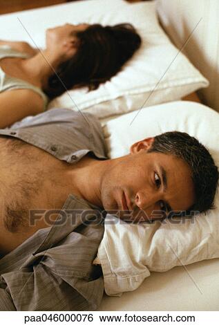 Man and woman lying in bed, heads on pillows, facing opposite directions, head and shoulders View Large Photo Image Stock Photograph - Man and woman lying in bed, heads on pillows, facing opposite directions, head and shoulders. Fotosearch