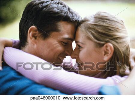 Stock Image - Man and woman smiling, foreheads and noses touching, side view, close-up. Fotosearch