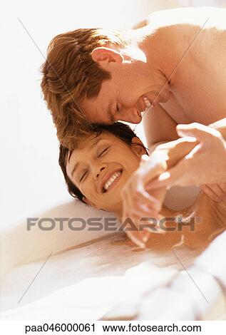 Stock Image - Man leaning head against woman in bathtub, both smiling. Fotosearch