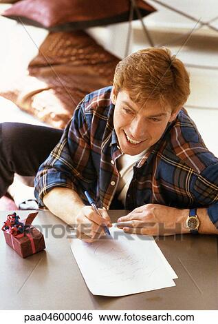 Stock Photograph - Man sitting at table, writing, high angle view. Fotosearch