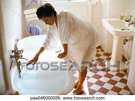 Woman bending over side of bathtub, hand under tap View Large Photo Image Stock Photograph - Woman bending over side of bathtub, hand under tap. Fotosearch