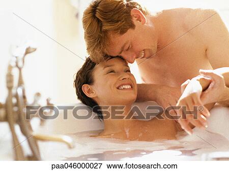 Woman in bubble bath, head on edge of tub, man with forehead against woman's, holding her arm View Large Photo Image Stock Photo - Woman in bubble bath, head on edge of tub, man with forehead against woman's, holding her arm. Fotosearch