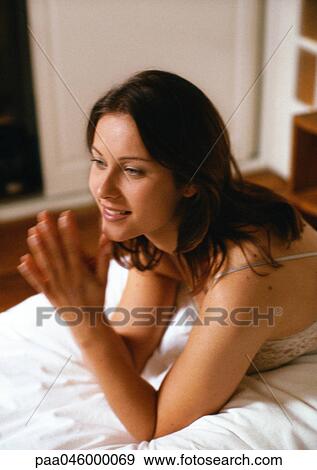 Woman propped up on elbows on bed with hands together, close-up, blurred motion View Large Photo Image Stock Photo - Woman propped up on elbows on bed with hands together, close-up, blurred motion. Fotosearch