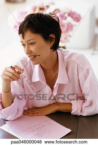 Woman sitting at table, writing and holding glasses, portrait View Large Photo Image Stock Photo - Woman sitting at table, writing and holding glasses, portrait. Fotosearch