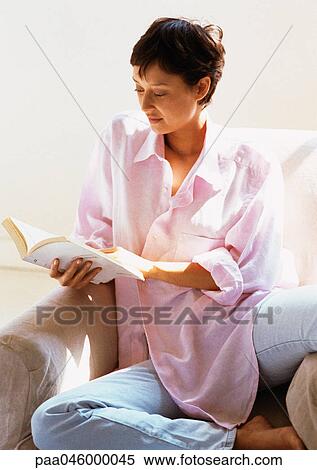 Woman sitting in armchair, reading book View Large Photo Image Stock Photography - Woman sitting in armchair, reading book. Fotosearch