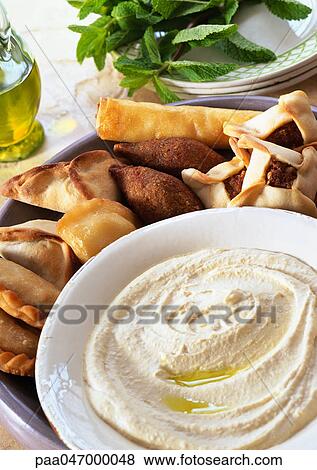 Bowl of hummus with middle eastern turnovers, close-up View Large Photo Image Stock Photo - Bowl of hummus with middle eastern turnovers, close-up. Fotosearch