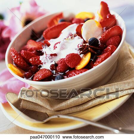 Stock Image - Bowl of summer fruits with cream and spices, close-up. Fotosearch