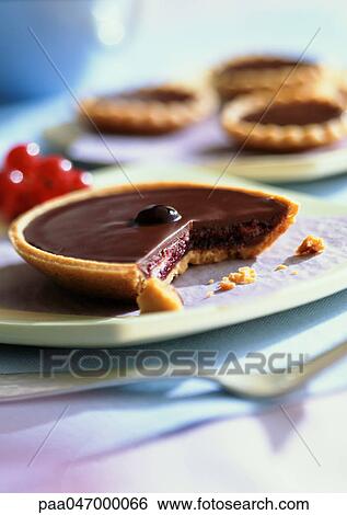 Stock Photograph - Chocolate tartlets, one in foreground with bite missing, close-up. Fotosearch