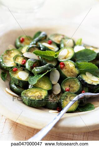 Stock Photo - Cooked zucchini with mint and almonds in bowl, close-up. Fotosearch