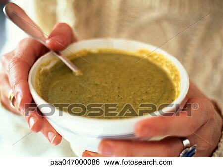 Stock Photograph - Hands holding bowl of leek soup, close-up. Fotosearch
