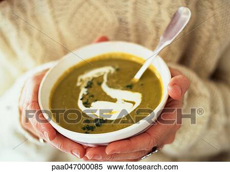 Stock Photography - Hands holding bowl of watercress soup, close-up. Fotosearch