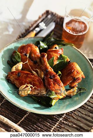 Stock Photography - Plate of chicken on tray with glass of beer and silverware, close-up. Fotosearch