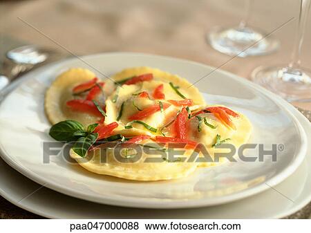 Stock Photo - Plate of ravioli with tomatoes and basil, close-up. Fotosearch