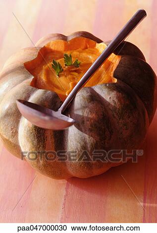 Stock Image - Pumpkin soup in pumpkin shell with ladle, close-up. Fotosearch
