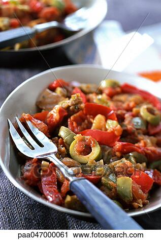 Stock Image - Red pepper and olive dish in bowl with fork, close-up. Fotosearch