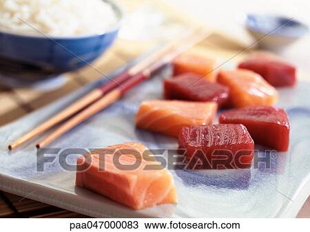 Sashimi on plate with chopsticks, bowl of rice in background, close-up View Large Photo Image Stock Image - Sashimi on plate with chopsticks, bowl of rice in background, close-up. Fotosearch