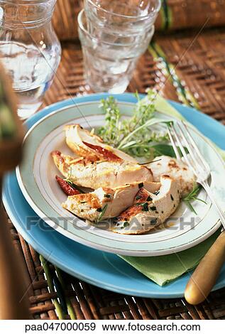 Stock Photo - Slices of chicken with tarragon on plate with tableware. Fotosearch