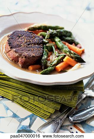 Stock Photograph - Steak with asparagus and carrots on plate, close-up. Fotosearch