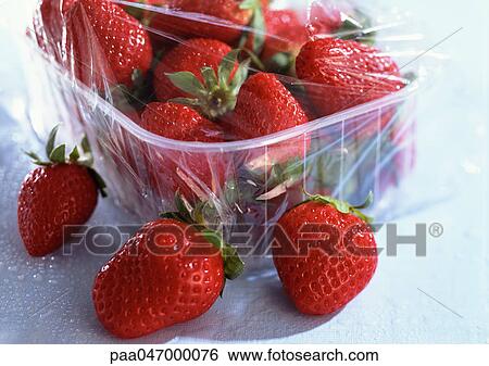 Stock Photograph - Strawberries in foreground and in plastic container, close-up. Fotosearch