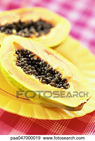 Stock Photo - Two papaya halves on yellow plate, close-up. Fotosearch