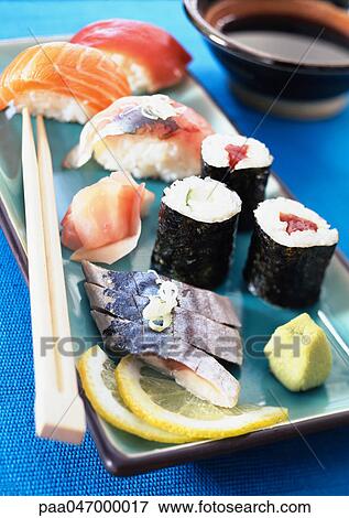 Stock Photo - Various types of sushi on plate with chopsticks, close-up. Fotosearch
