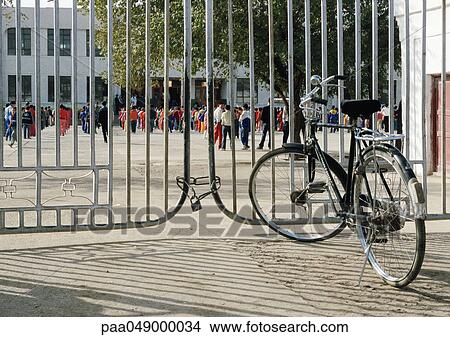 Bicycle in front of gate, children in schoolyard in background View Large Photo Image Picture - Bicycle in front of gate, children in schoolyard in background. Fotosearch