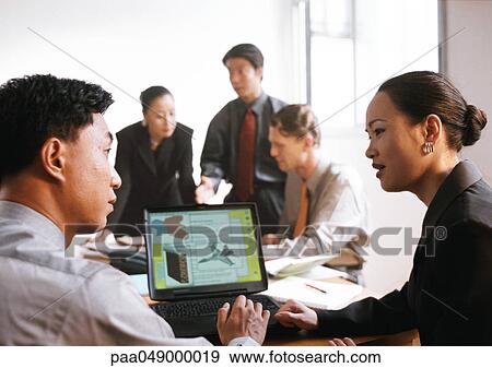 Businessman and woman in front of computer screen, three people in background View Large Photo Image Stock Photo - Businessman and woman in front of computer screen, three people in background. Fotosearch