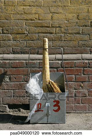 Stock Image - China, broom and dustpan, brick wall in background, close-up. Fotosearch