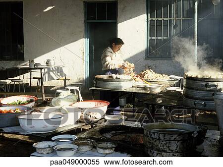 Stock Photography - China, Xinjiang Province, Turpan, woman handling noodles in kitchen. Fotosearch