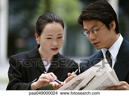 Picture - Man and woman looking at newspaper. Fotosearch