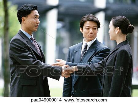 Picture - Man and woman shaking hands, other man introducing them. Fotosearch